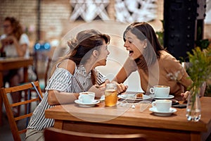 Girlfriends having a very cheerful conversation in cafe. Laughing, giggling