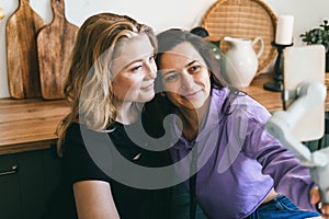 Girlfriends laugh merrily and take selfies in the kitchen.