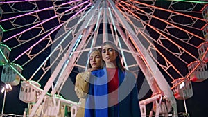 Girlfriends posing ferris wheel at night. Two models resting illuminated funfair