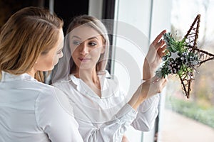 Girlfriends probing Christmas star decoration in window