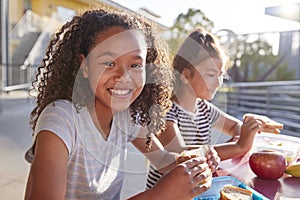 Girlfriends at school lunch table, one smiling to camera