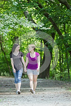 Girlfriends taking a walk through the park, vertical