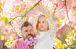 Girlish leisure concept. Father and daughter on happy faces hugs, sakura background. Child and man with tender pink