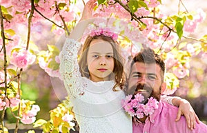 Girlish leisure concept. Girl with dad near sakura flowers on spring day. Child and man with tender pink flowers in