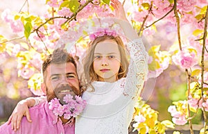 Girlish leisure concept. Girl with dad near sakura flowers on spring day. Child and man with tender pink flowers in