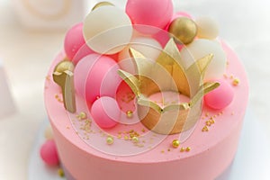 Girlish pink cake with baubles, golden crown and number 1.
