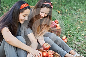 Girls with Apple in the Apple Orchard. Beautiful sisters with Organic Apple in the Orchard. Harvest Concept. Garden, teenagers