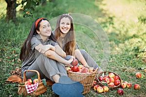 Girls with Apple in the Apple Orchard. Beautiful sisters with Organic Apple in the Orchard. Harvest Concept. Garden, teenagers