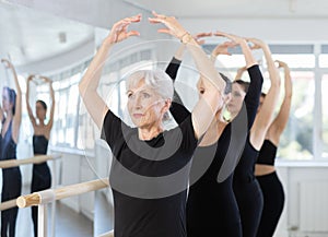 Girls in ballet class perform fifth position with participation of mature female mentor