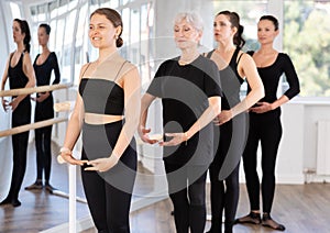 Girls in ballet class perform first position with participation of mature female mentor