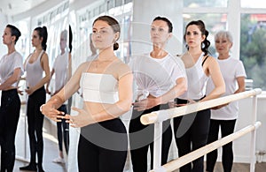 Girls in ballet class perform first position with participation of mature female mentor