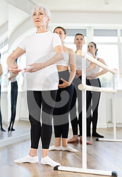 Girls in ballet class perform first position with participation of mature female mentor