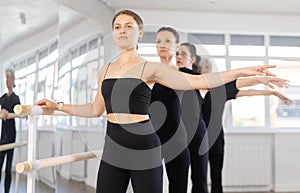 Girls in ballet class perform second position with participation of mature female mentor