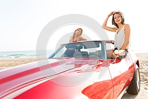 Girls at beach in sports car convertible having