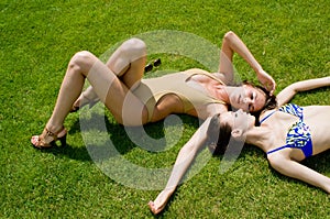 Girls in beachwear taking sunbath on the grass