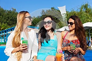 Girls with beverages on summer party near the pool
