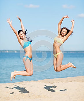 Girls in bikini jumping on the beach