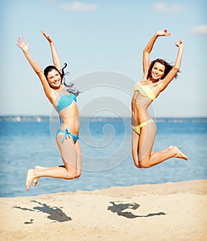 Girls in bikini jumping on the beach