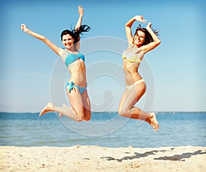 Girls in bikini jumping on the beach