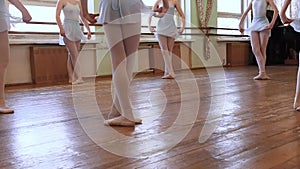 Girls in blue ballet suits stand in third position and begin dancing in circle on floor of frayed ballet classroom. HD