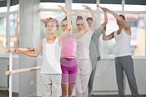 Girls and boys in ballet class perform third position under male teacher guidance.