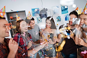 Girls and boys celebrate birthday. They drink champagne from glasses and have fun.