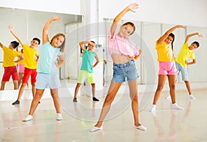 Girls and boys doing dance workout during group class in fitness center