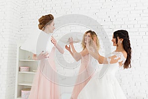 Girls celebrate a bachelorette party of bride. bridesmaids fighting pillows on white brick wall background