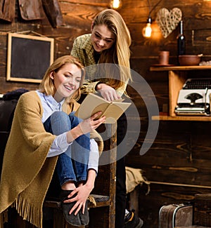 Girls with cheerful faces laughing about funny moment in book. Mom and daughter reading together on cold winter evening