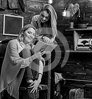 Girls with cheerful faces laughing about funny moment in book. Mom and daughter reading together on cold winter evening