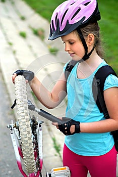 Girls child cycling pump up bicycle tire.