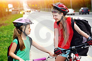 Girls children cycling on yellow bike lane. There are cars on road.