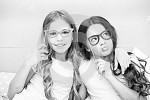 Girls children posing with grimaces photo booth props. Pajamas party concept. Girls friends having fun pajamas party