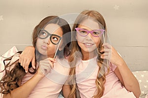 Girls children posing with grimaces photo booth props. Pajamas party concept. Girls friends having fun pajamas party