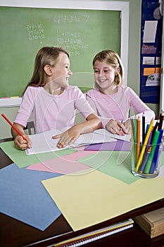 Girls in classroom doing schoolwork, writing