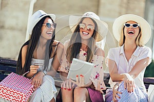 Girls with colorful shopping bags using digital tablet and credit card