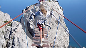 Girls crossing the chasm on the rope bridge. Black sea background, Crimea