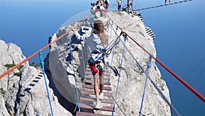 Girls crossing the chasm on the rope bridge. Black sea background, Crimea