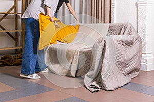 Girls designers decorate the living room. Set the yellow pillows on the sofa.