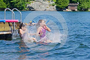 Girls dive bombing friend off dock into lake photo