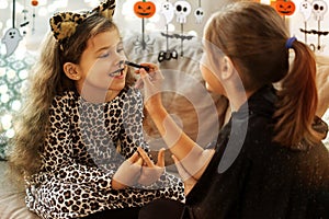 girls doing face painting on halloween at home