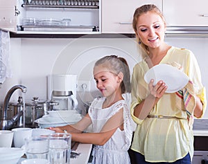 Girls doing and wiping dishes in kitchen