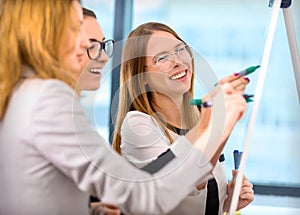 Girls draw business plans on a whiteboard