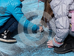 Girls drawing blue chalk asphalt