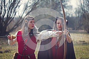Girls dressed as medieval era teaching archery at the field
