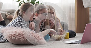 Girls eating popcorn and watching media content on laptop