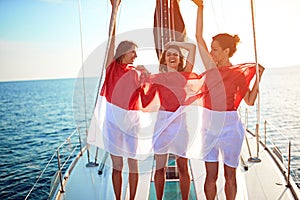 Girls enjoy the vacation on a yacht with flag