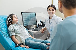 Girls father talking to doctor conducting electroencephalography photo