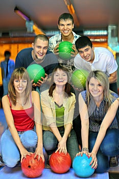 Girls and fellows stand with ball in bowling club