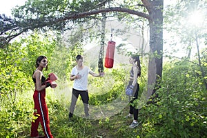 Girls fighting boxing outside with coach in green park, sport summer people concept